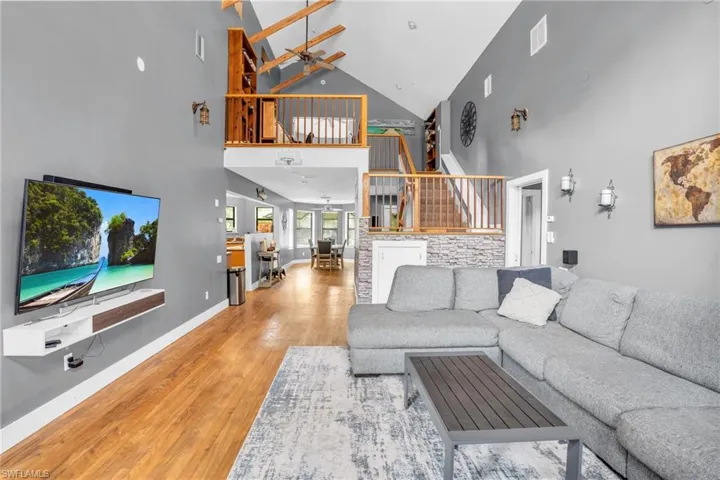 Living room featuring light hardwood / wood-style flooring, ceiling fan, and high vaulted ceiling