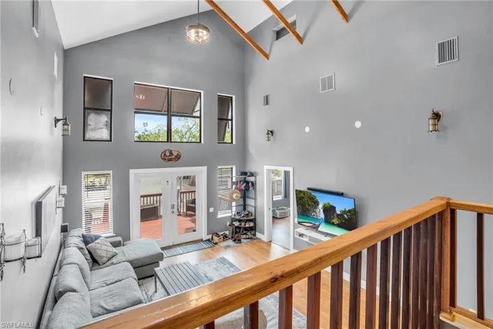 Living room featuring hardwood / wood-style floors, high vaulted ceiling, and french doors