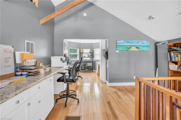 Office area with light hardwood / wood-style flooring and high vaulted ceiling