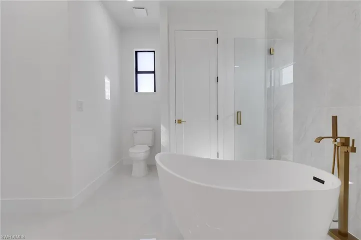 Bathroom with a freestanding tub and marble finish floors