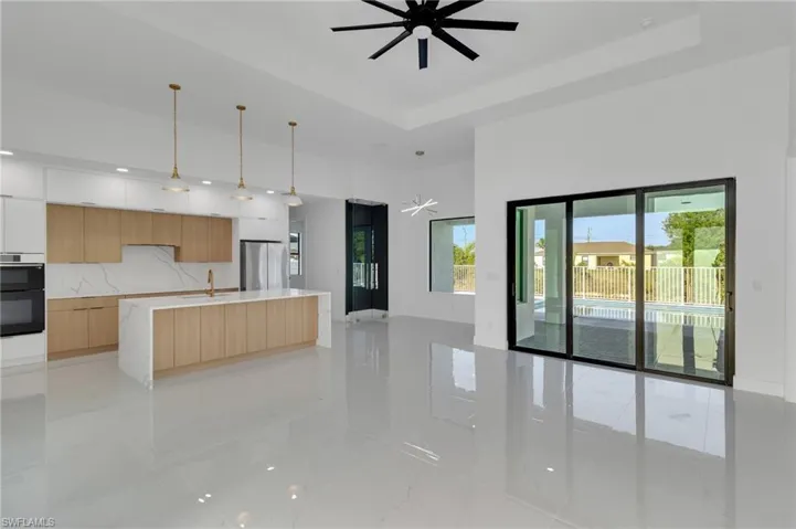Kitchen featuring modern cabinets, freestanding refrigerator, a ceiling fan, open floor plan, and light brown cabinetry