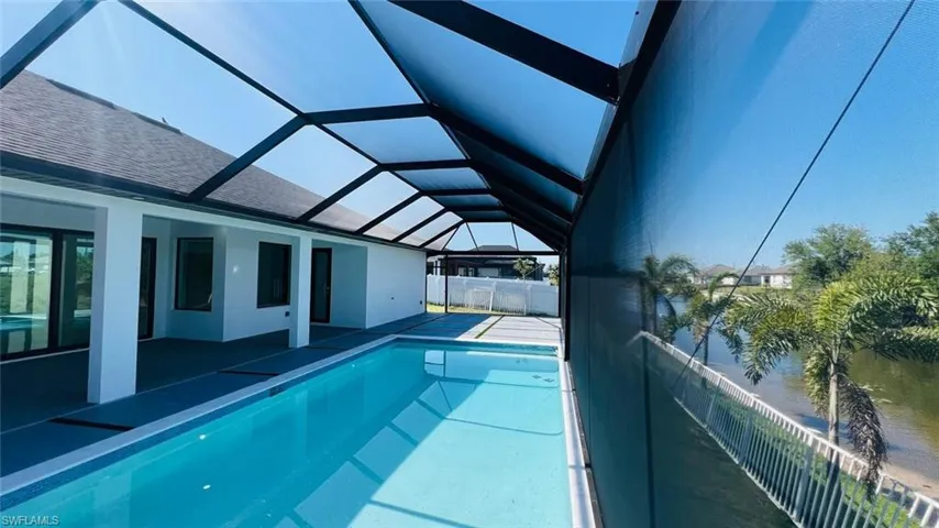 View of pool with glass enclosure and a patio