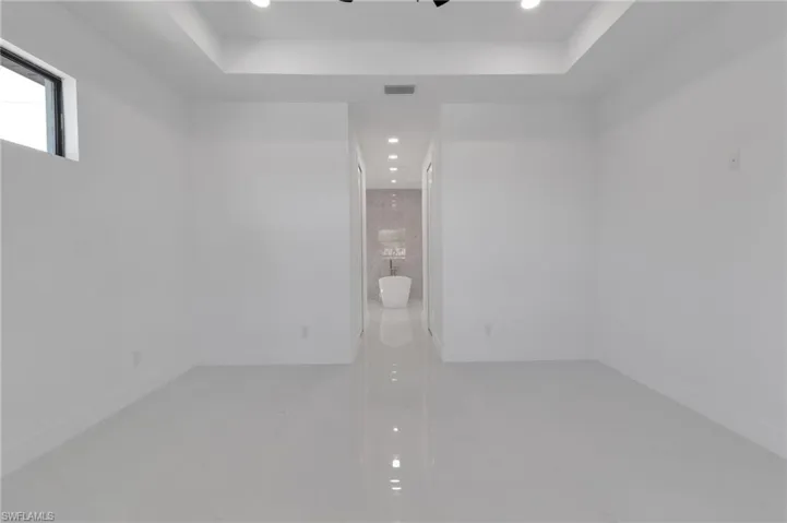 Unfurnished room with recessed lighting, a raised ceiling, and marble finish flooring