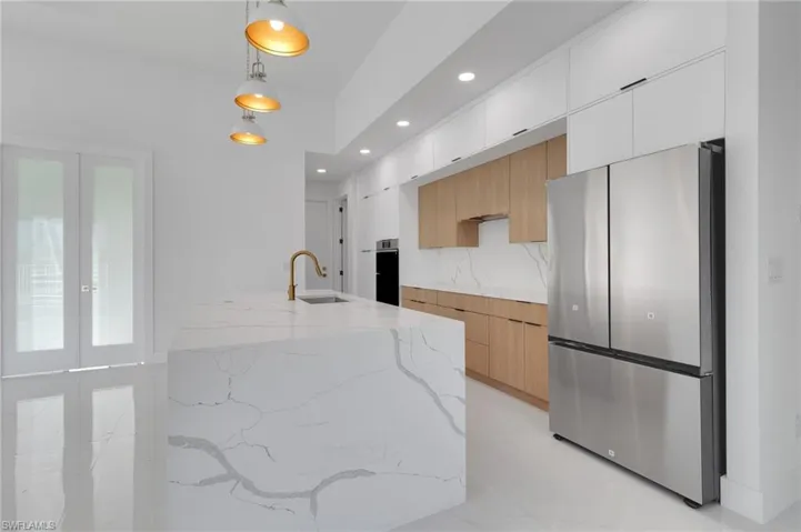 Kitchen featuring stainless steel appliances, modern cabinets, recessed lighting, light stone counters, and pendant lighting