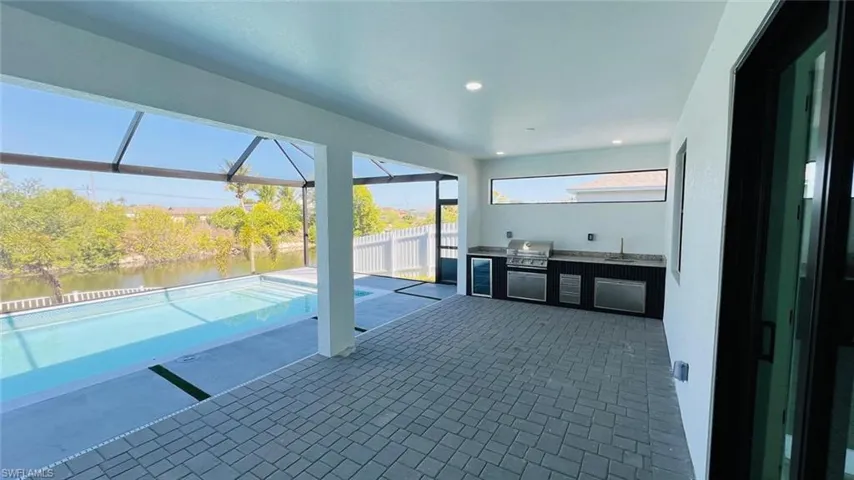 View of patio with an outdoor kitchen, a lanai, and a water view