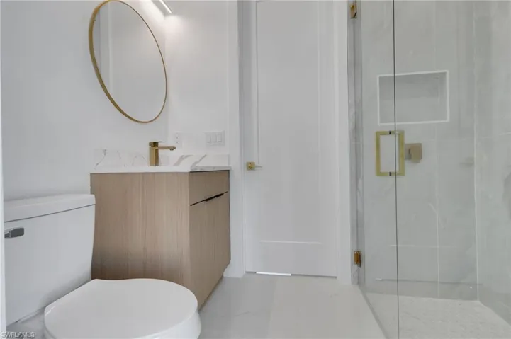 Full bath featuring a marble finish shower, vanity, and marble finish floors