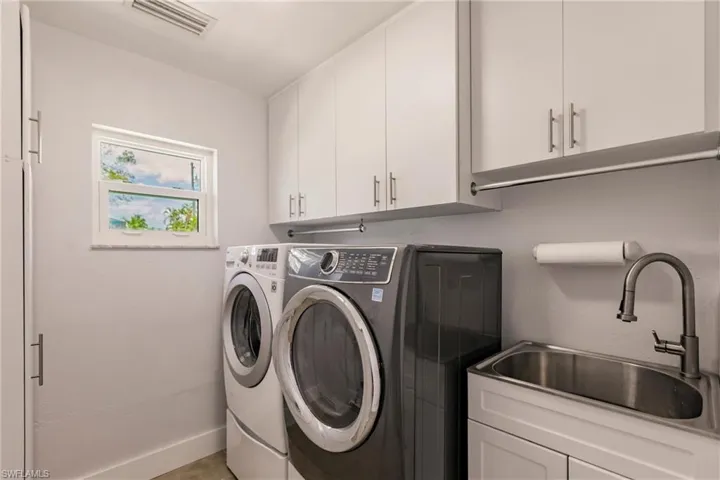 Laundry area featuring cabinets, sink, and washing machine and dryer