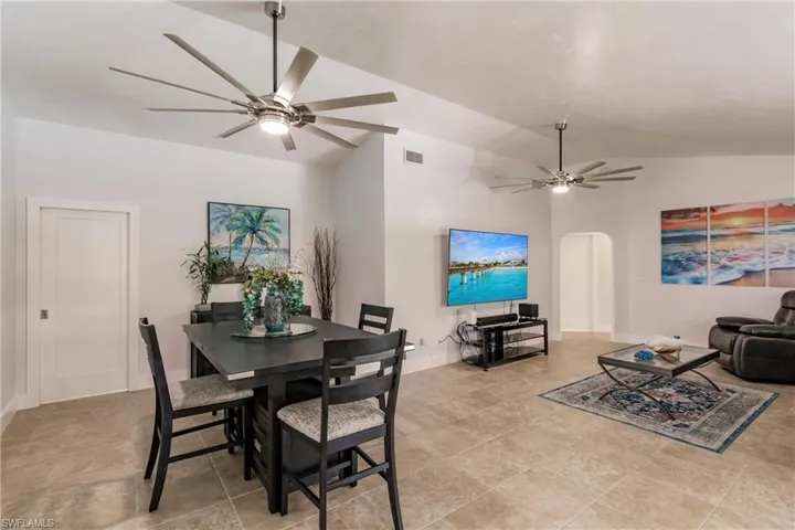 Tiled dining space with ceiling fan and lofted ceiling