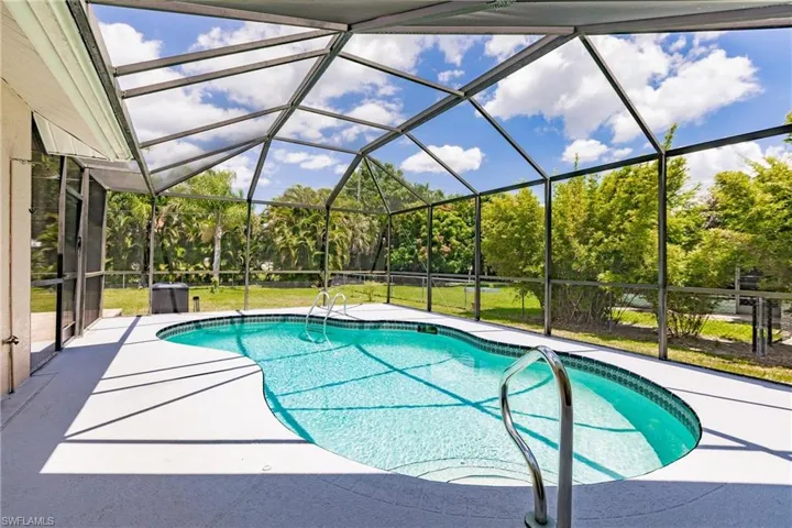 View of swimming pool featuring glass enclosure, a patio area, and a yard
