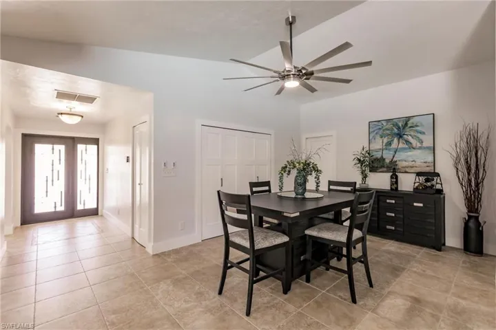 Dining room with ceiling fan, lofted ceiling, and light tile floors