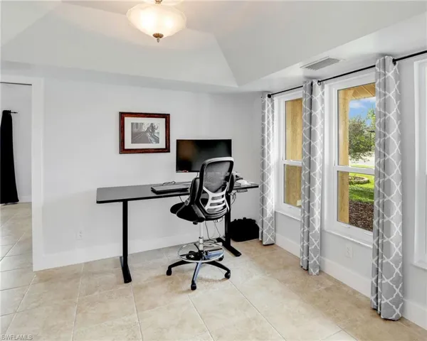 Home office with a raised ceiling and light tile floors