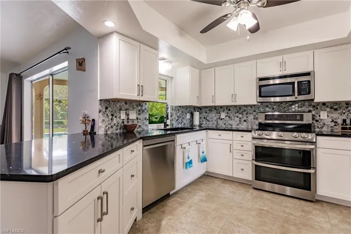 Kitchen featuring white cabinets, appliances with stainless steel finishes, sink, and backsplash