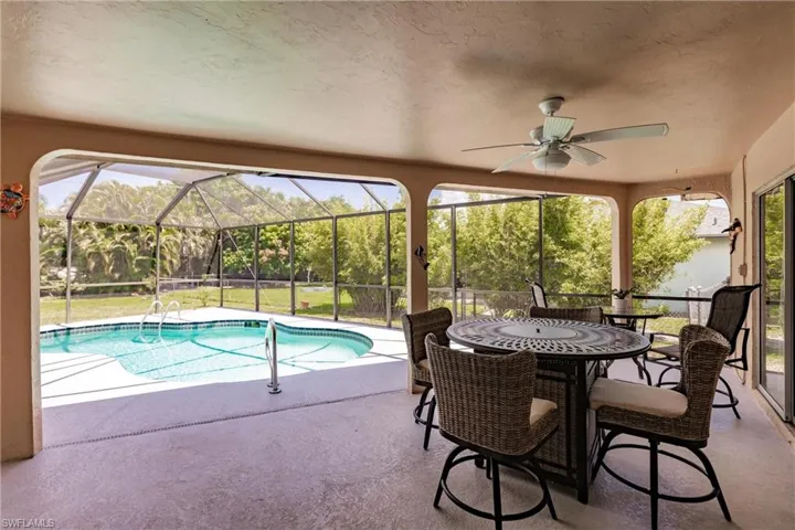 View of swimming pool with ceiling fan, glass enclosure, and a patio area