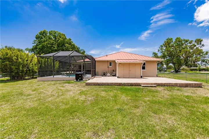 Back of house featuring a lanai, a patio area, and a yard