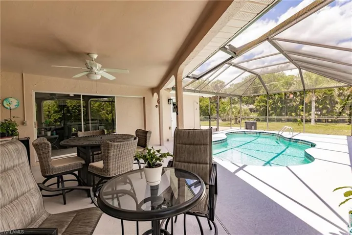 View of swimming pool featuring a patio, glass enclosure, and ceiling fan