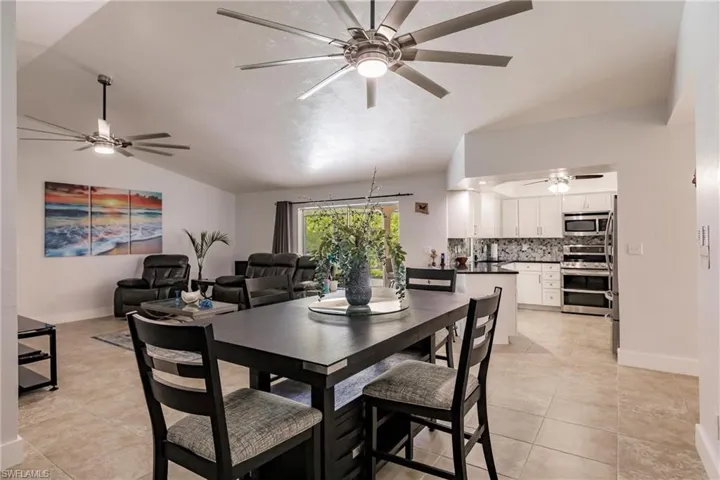 Tiled dining area featuring ceiling fan and lofted ceiling