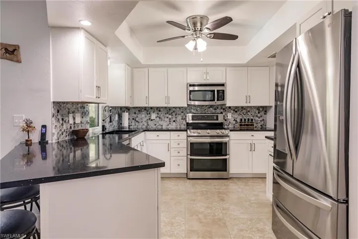 Kitchen with appliances with stainless steel finishes, kitchen peninsula, a kitchen bar, and a raised ceiling