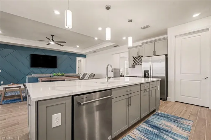 Kitchen with gray cabinets, wood tiled floors, stainless steel appliances, a ceiling fan, and ornamental molding