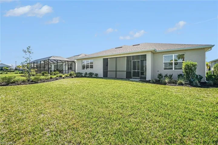 Rear view of property featuring a sunroom, stucco siding, a lawn, and a lanai