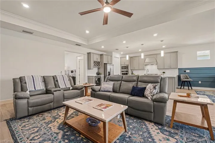 Living area featuring wood finished floors, a ceiling fan, crown molding, recessed lighting, and beverage cooler