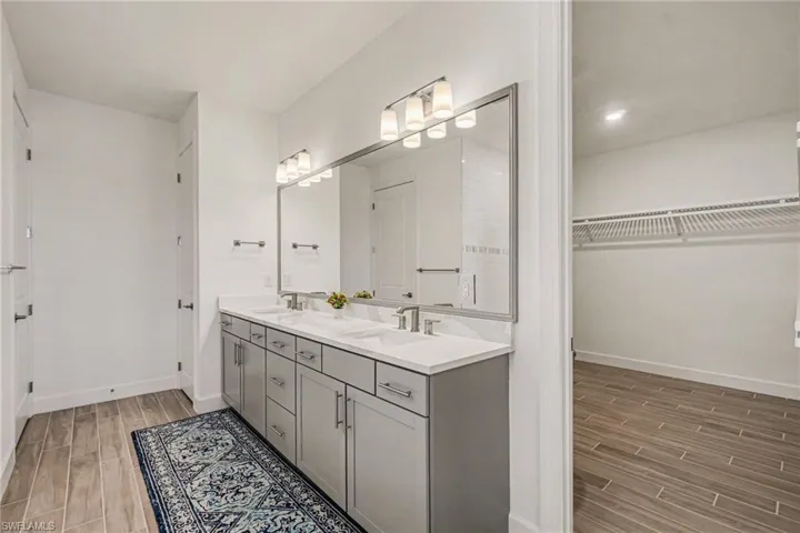 Full bathroom featuring wood finish floors, double vanity, and a walk in closet