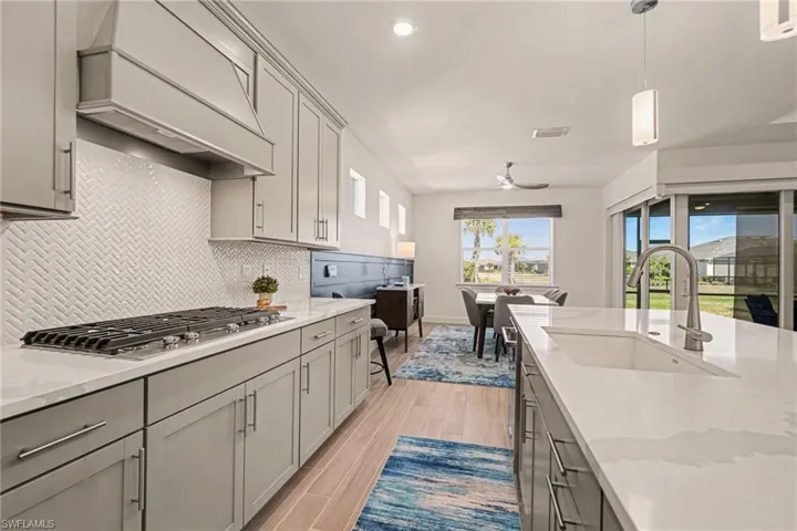 Kitchen featuring gray cabinets, light stone countertops, decorative light fixtures, and stainless steel gas cooktop