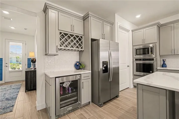 Kitchen with gray cabinetry, recessed lighting, stainless steel appliances, beverage cooler, and wood finish floors