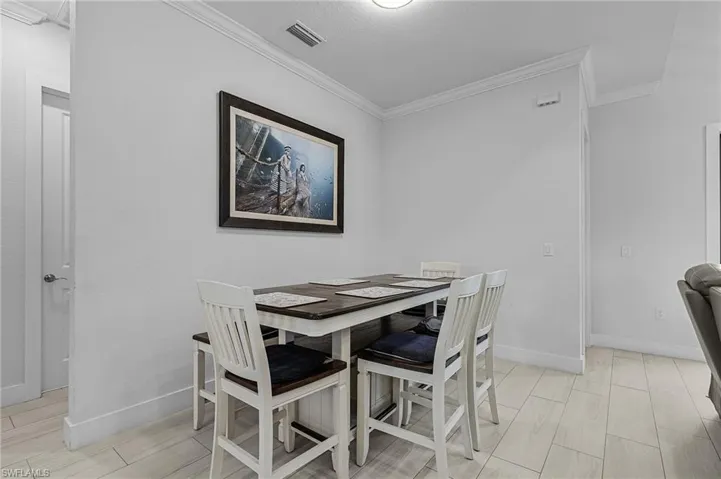 Dining area with visible vents, crown molding, and baseboards