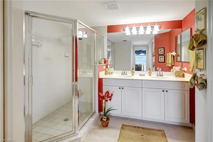 Bathroom featuring double vanity, a sink, a shower stall, and tile patterned floors
