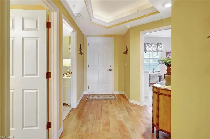 Entrance foyer with visible vents, a raised ceiling, light wood-style flooring, and baseboards