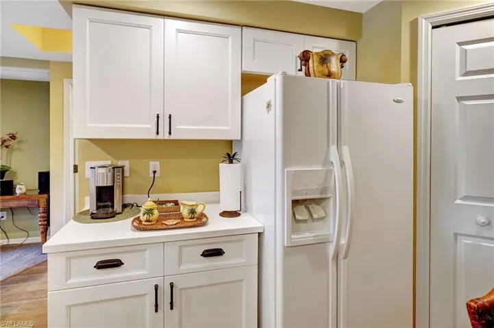 Kitchen featuring white fridge with ice dispenser, light wood-style flooring, light countertops, and white cabinetry