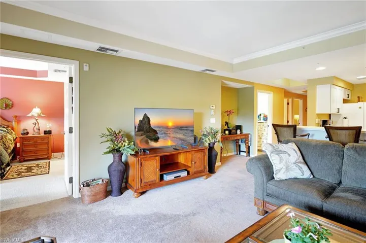 Living room featuring ornamental molding, visible vents, and light carpet