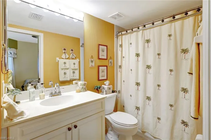 Bathroom with toilet, a shower with curtain, visible vents, and vanity