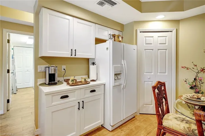 Kitchen featuring light countertops, visible vents, white cabinetry, white fridge with ice dispenser, and light wood-type flooring