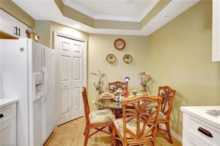 Dining room featuring light wood-type flooring, baseboards, a tray ceiling, and ornamental molding