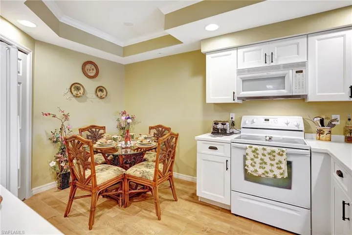 Kitchen with light countertops, white appliances, white cabinetry, and crown molding