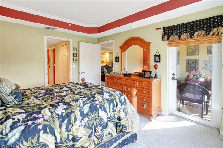 Carpeted bedroom featuring access to exterior, visible vents, and ornamental molding