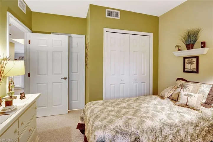 Bedroom with a closet, visible vents, and light colored carpet