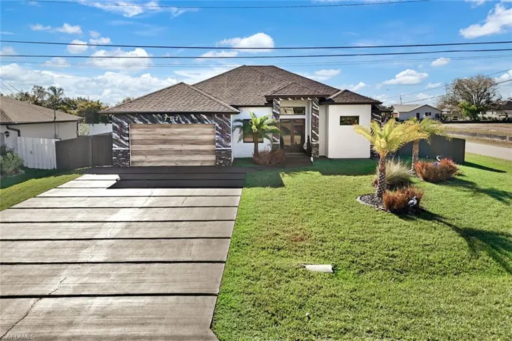 View of front of property with stucco siding, a shingled roof, a front yard, and fence