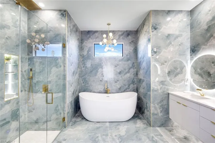 Bathroom featuring vanity, a shower stall, a healthy amount of sunlight, and a freestanding bath