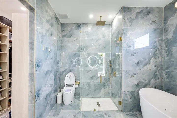 Full bathroom featuring visible vents, a soaking tub, tile walls, and a shower stall