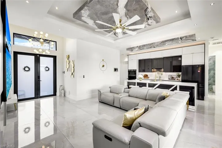 Living area with a tray ceiling, marble finish floor, and french doors