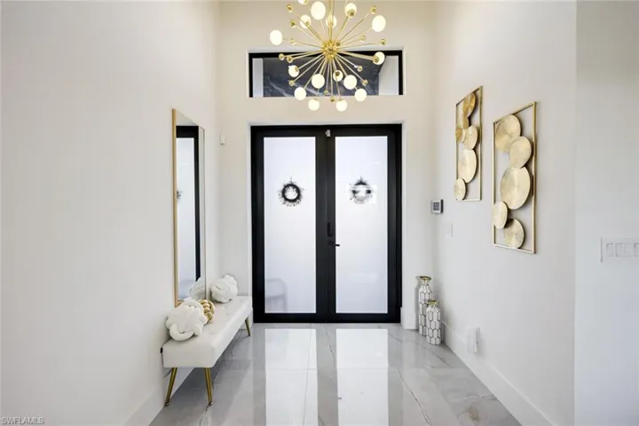Foyer with a chandelier, marble finish floor, french doors, and baseboards
