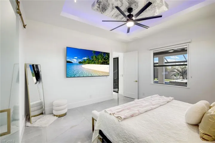 Bedroom with marble finish floor, ceiling fan, a raised ceiling, and baseboards