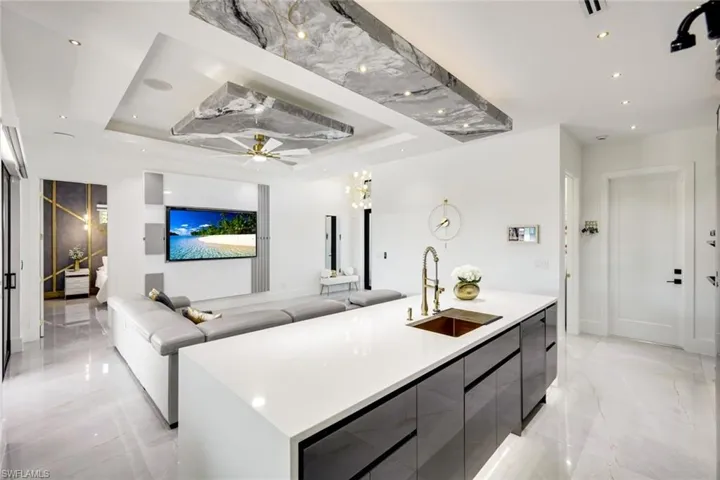 Kitchen with a raised ceiling, modern cabinets, marble finish floor, and a sink