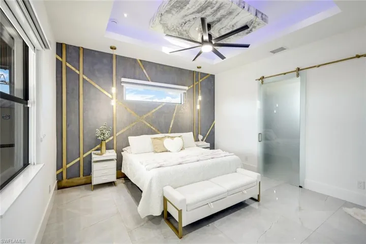 Bedroom featuring baseboards, a barn door, a raised ceiling, and visible vents