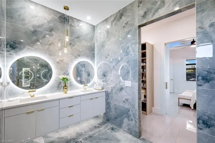 Bathroom featuring double vanity, tile walls, and a sink