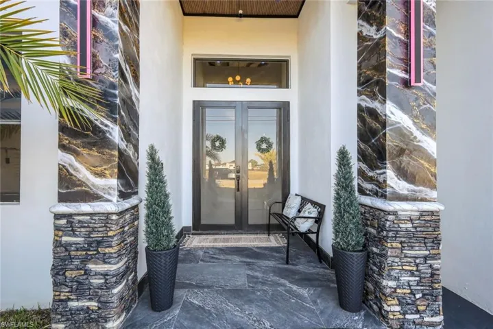 Entrance to property featuring french doors, stone siding, and stucco siding