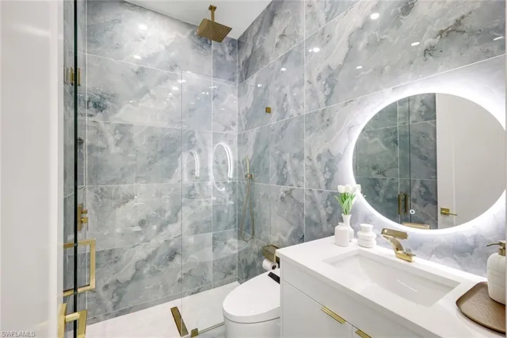 Full bathroom featuring toilet, tile walls, vanity, and walk in shower