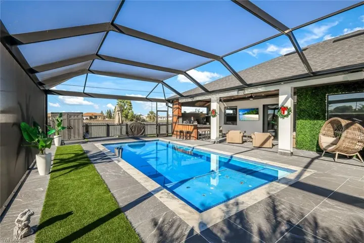 View of pool featuring glass enclosure, a patio, a gate, and fence